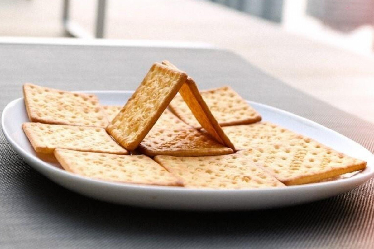 Cream crackers being stacked on a plate.