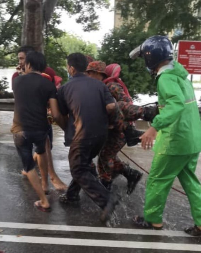 Firefighters saving their colleague from flood waters.