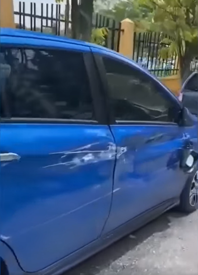 A blue car showing deep dents and scratches due to the lorry.