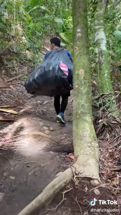 Hiker lifts a huge bag of trash over his shoulders.