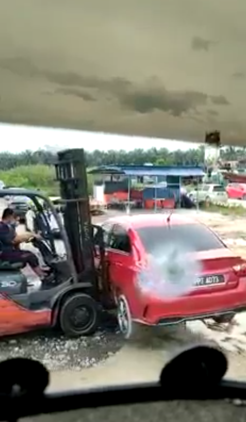 The illegally parked car being moved away by a forklift.