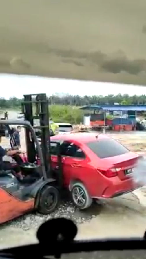 The illegally parked car being moved away by a forklift.