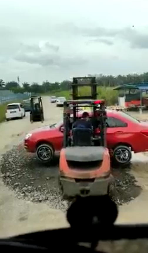 The illegally parked car being moved away by a forklift.