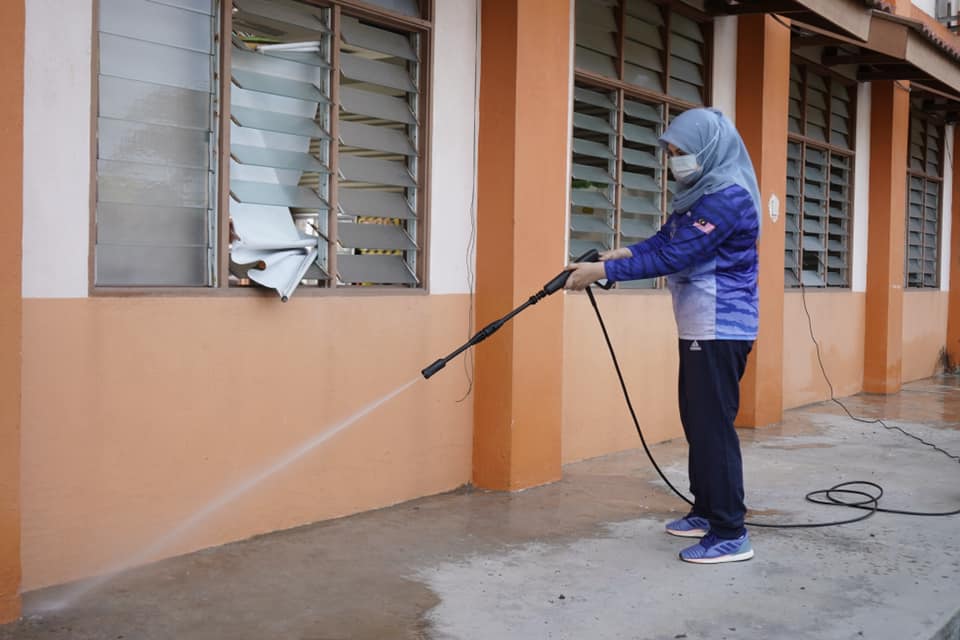 A photo of Datuk Seri Rina Harun hosing down a wall.