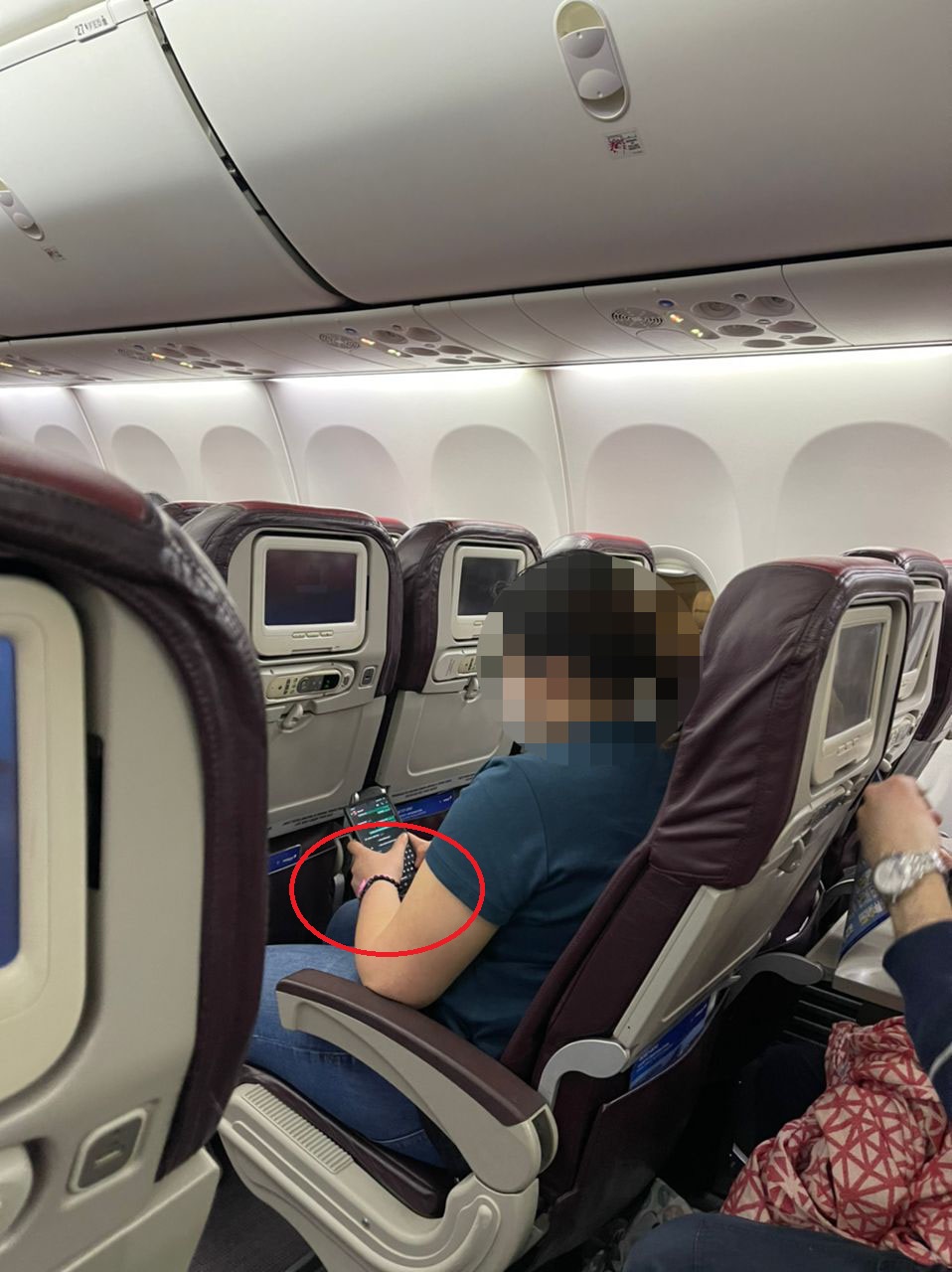 A passenger seen wearing a pink quarantine wristband on board a Malaysia Airlines flight.