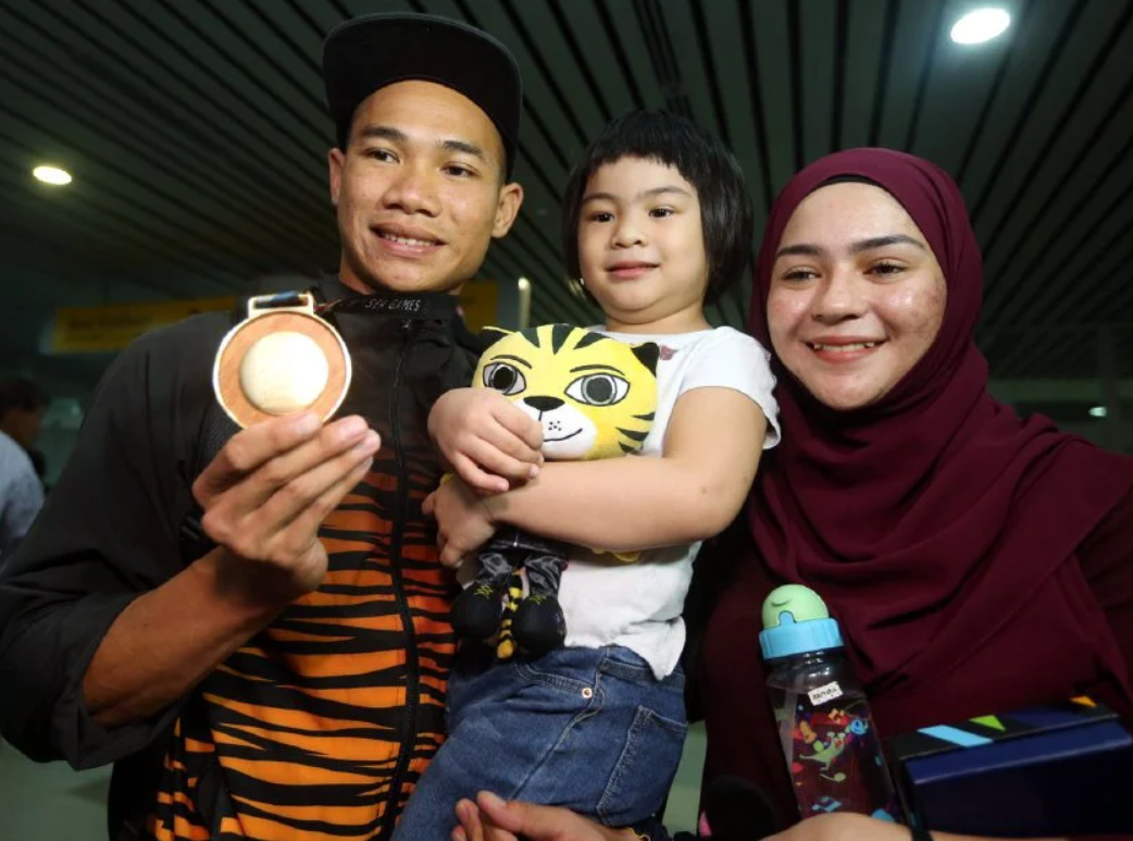 National athlete Rayzam Shah Wan Sofian with his wife and child.