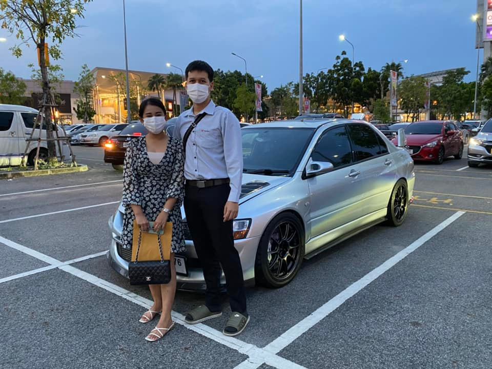 The happy couple standing in front of their Mitsubishi Lancer Evolution 8.