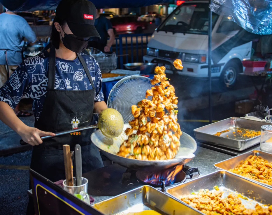 A hawker preparing salted egg snacks at a night market in KL. 