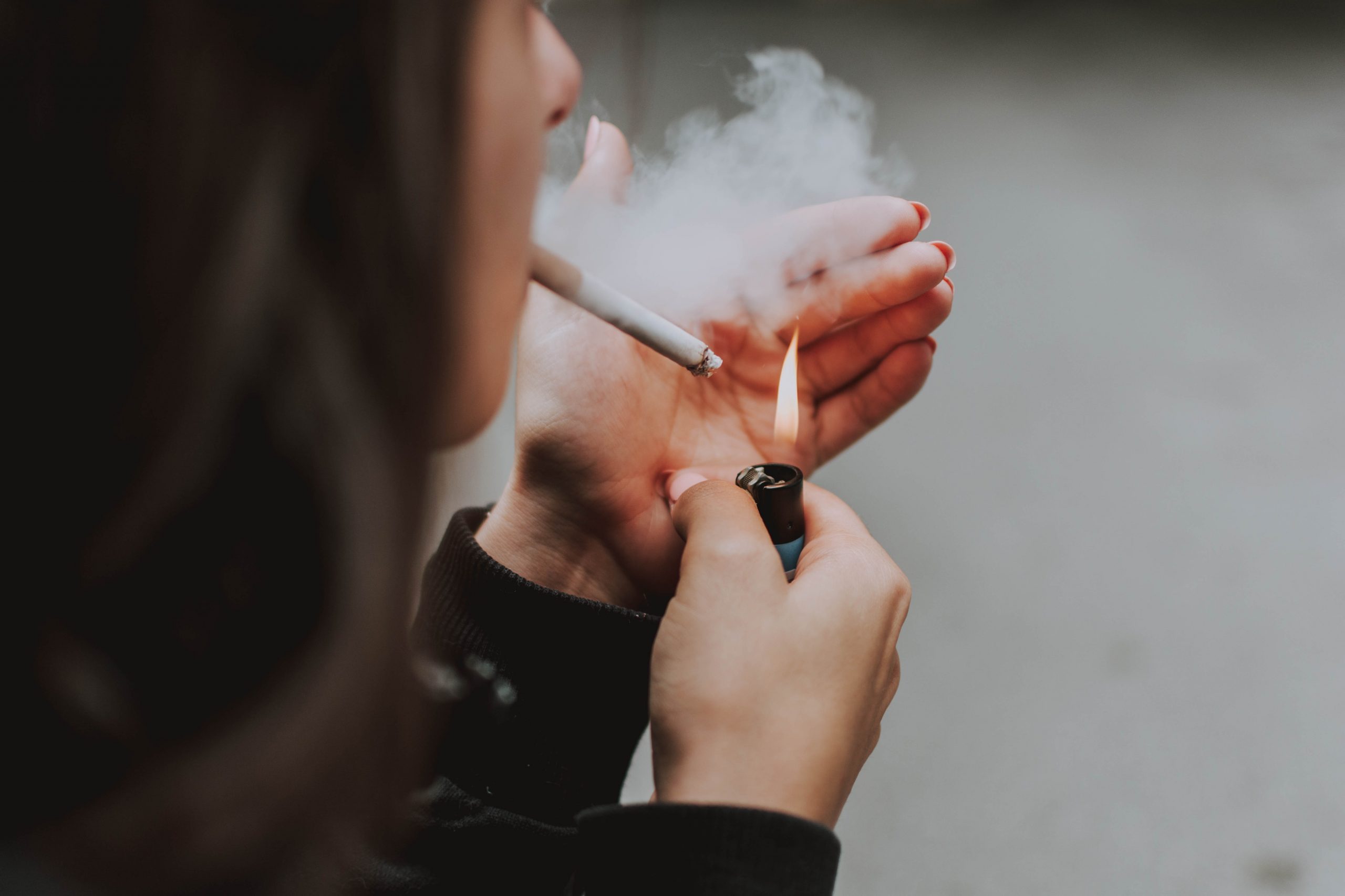 A woman lighting up a cigarette.