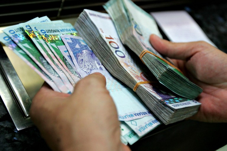 An individual counting RM50 bank notes. 