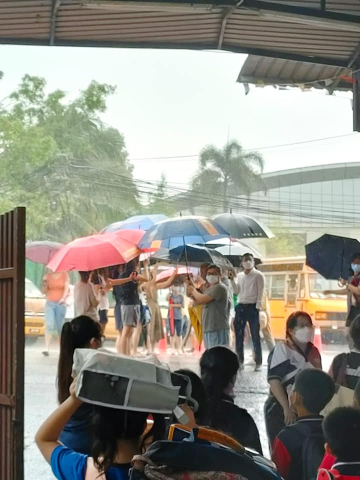 Parents at Johor school work together to shield students from the rain. Image credit: SJK (C) Foon Yew 2