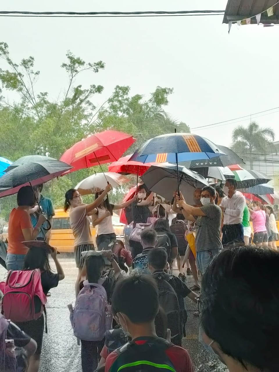 Parents at Johor school work together to shield students from the rain. Image credit: SJK (C) Foon Yew 2
