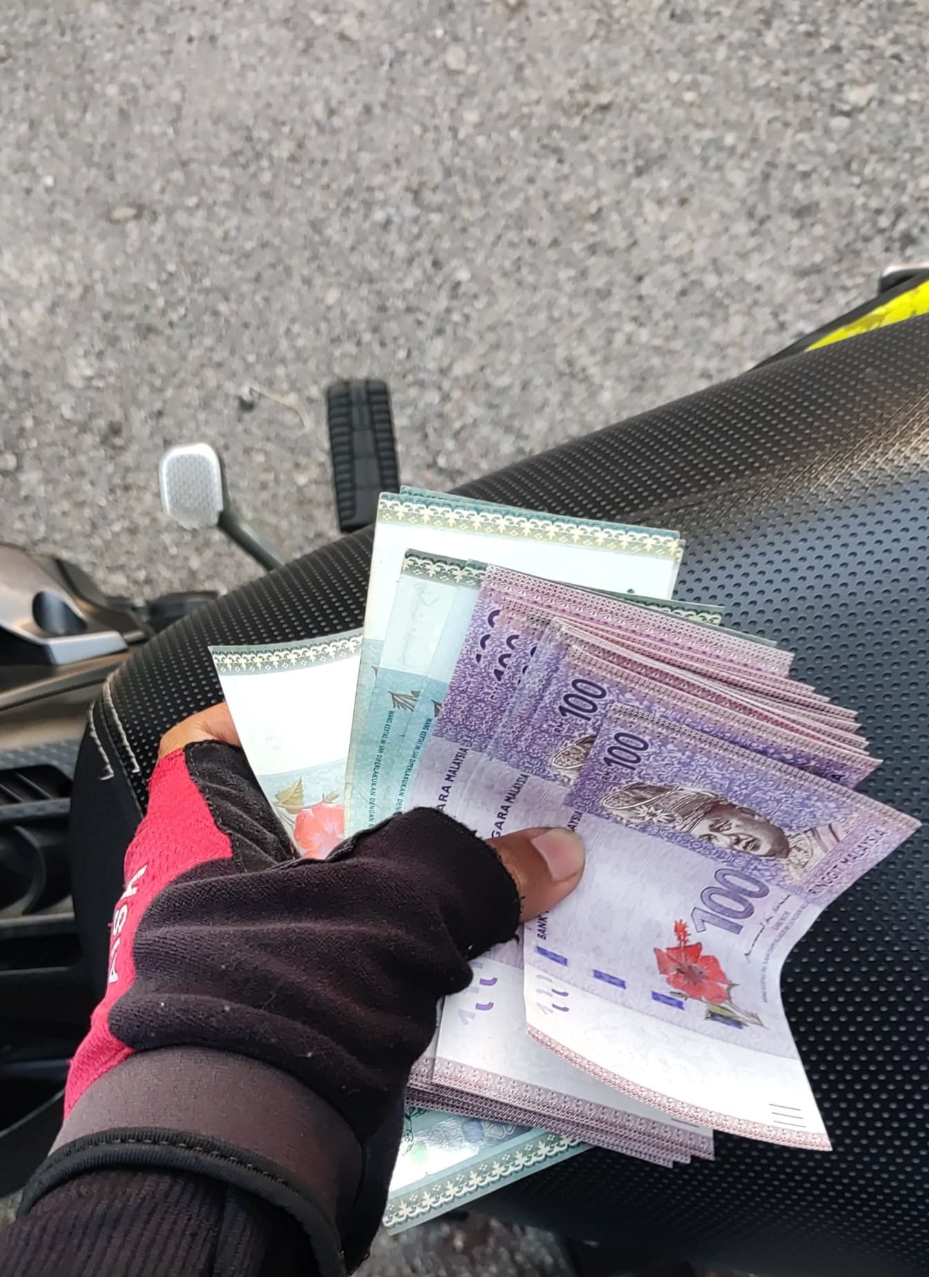 A food delivery rider was scammed after receiving fake RM100 bank notes. Image credit: Asyraff Akra