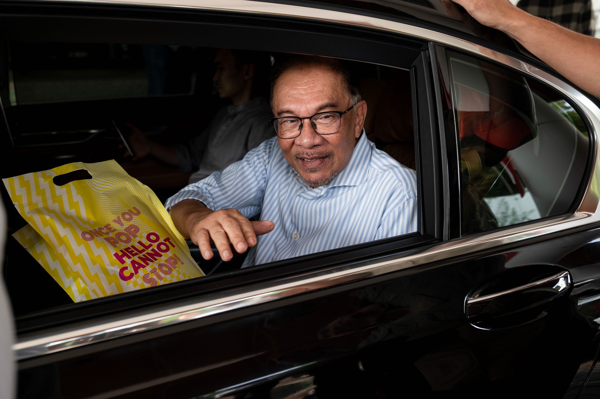 Anwar Ibrahim hands out GSC popcorn to members of the press as he leaves his office. Image credit: CNA